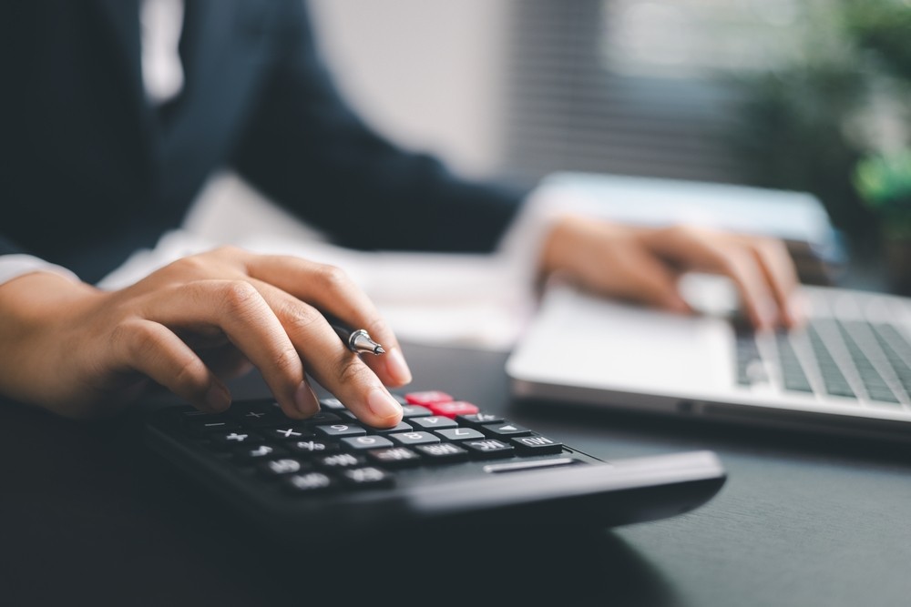 Professional typing on a calculator and a laptop at a desk