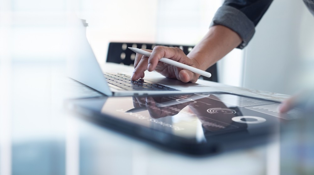 Businessman working on laptop, using mobile phone at modern office.