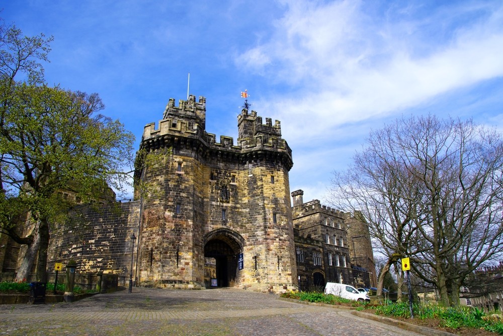 Photo of Lancaster Castle with blue sky and trees around