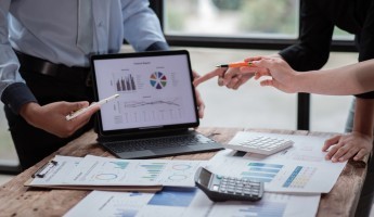 Staff discussing information presented on a laptop around a table