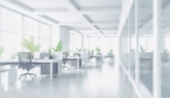 Blurred image of an empty office space with chairs and monitors