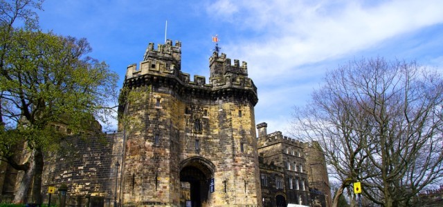 Photo of Lancaster Castle with blue sky and trees around