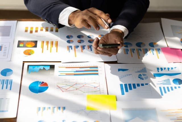 Person looking over multiples documents at a desk.