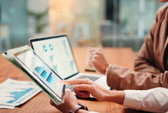 Two people looking over online graphs and documents