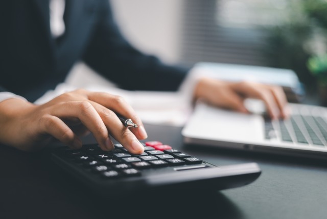 Professional typing on a calculator and a laptop at a desk